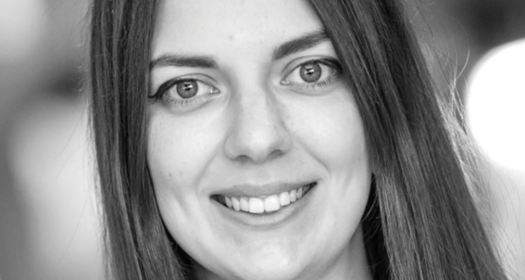 Black and white image featuring a female figure in the spotlight, with a softly lit background.