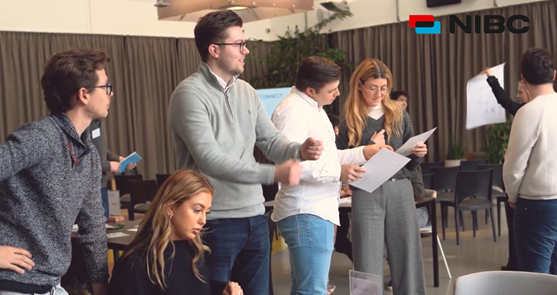 Group of people during a brainstorming session, with notes and presentation materials on the table. NIBC logo in the top right corner.