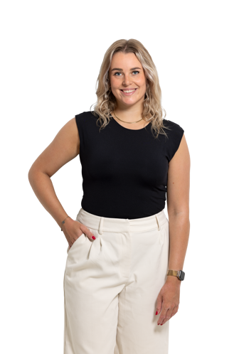 Kirsten in a black shirt and white pants, posing with her hand in her pocket.